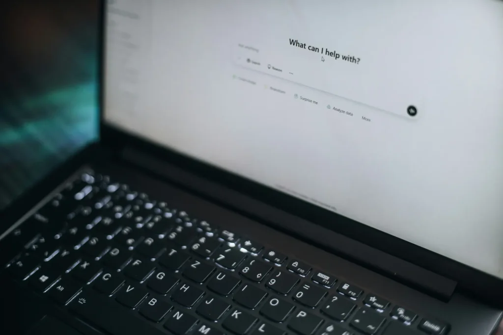 Close-up of a laptop displaying the ChatGPT start screen, with a dark keyboard and teal light beside it.